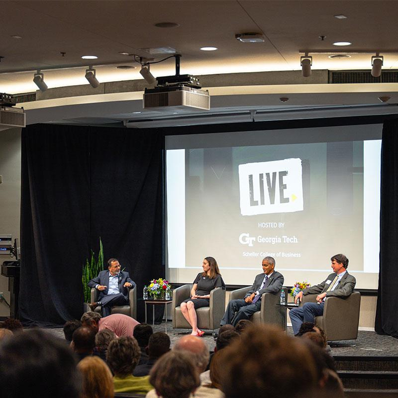 Four faculty members sitting on stage and talking.
